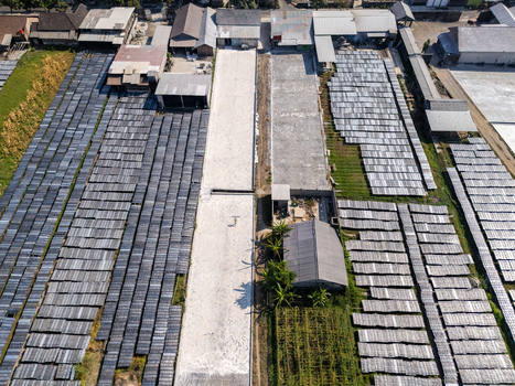 Aerial view of drying racks for traditional food products arranged in rows with a central path and surrounding buildings in Polanharjo Central Java Indonesia.