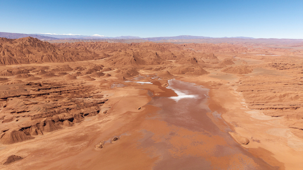 Aerial view of the arid desert landscape of Tolar Grande featuring reddish rock formations and salt flats under a clear blue sky in Tolar Grande Salta Province Argentina. Aerial view of the arid desert landscape of Tolar Grande featuring reddish rock formations and salt flats under a clear blue sky in Tolar Grande Salta Province Argentina.