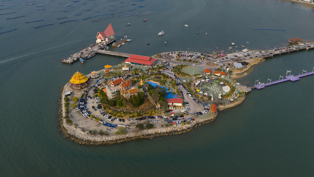 Aerial view of Koh Loi temple complex surrounded by the sea with a long pier parking areas and lush greenery in Si Racha Chon Buri Thailand. Aerial view of Koh Loi temple complex surrounded by the sea with a long pier parking areas and lush greenery in Si Racha Chon Buri Thailand.