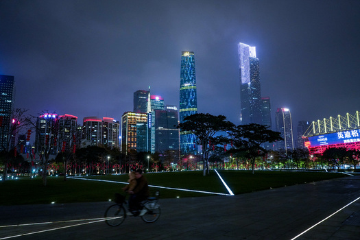 Guangzhou China 24 February 2024 View of the illuminated skyline of Guangzhou at night with a person riding a bicycle through a park in the foreground. Guangzhou China 24 February 2024 View of the illuminated skyline of Guangzhou at night with a person riding a bicycle through a park in the foreground.