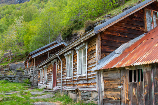 View of the historic Me Akneset mountain farm with weathered wooden buildings and stone foundations nestled on a lush green hillside in Stranda More og Romsdal Norway. View of the historic Me Akneset mountain farm with weathered wooden buildings and stone foundations nestled on a lush green hillside in Stranda More og Romsdal Norway.