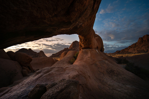 View of rugged sun kissed rock formations arching against a twilight sky casting shadows and revealing the stark beauty of the desert landscape Spitzkoppe Namibia.