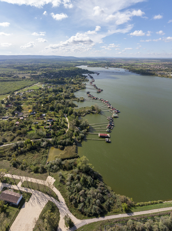 Aerial view of the Bokodi Floating Village with wooden houses on stilts over the calm lake surrounded by lush greenery and trees in Oroszlany Hungary. Aerial view of the Bokodi Floating Village with wooden houses on stilts over the calm lake surrounded by lush greenery and trees in Oroszlany Hungary.