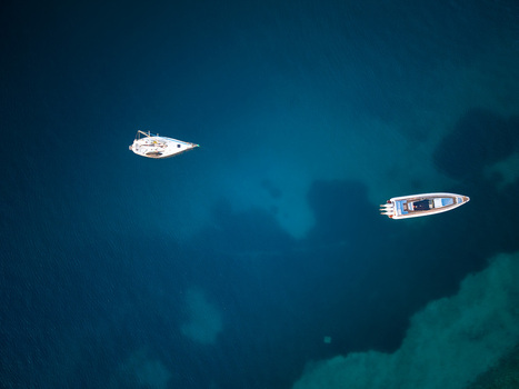 Aerial view of a sailboat and a motorboat floating on the deep blue crystal clear sea water Porto Palermo Qarku i Vlores Albania. Aerial view of a sailboat and a motorboat floating on the deep blue crystal clear sea water Porto Palermo Qarku i Vlores Albania.