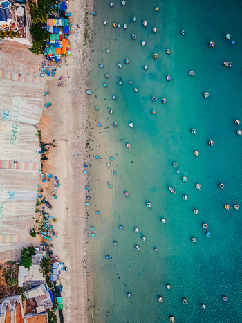 Aerial view of traditional round basket boats floating in the turquoise waters off the sandy coast of Mui Ne fishing village in Vietnam. Aerial view of traditional round basket boats floating in the turquoise waters off the sandy coast of Mui Ne fishing village in Vietnam.