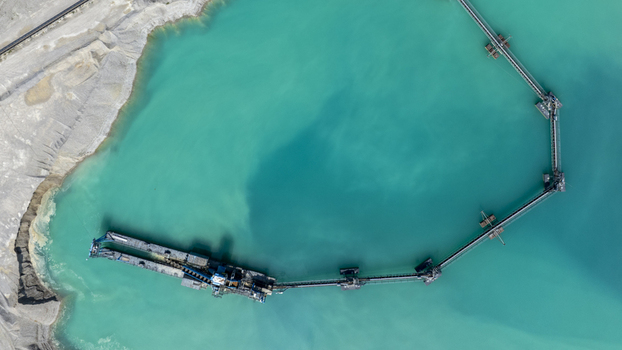 Aerial view of a gravel pit with turquoise water and industrial conveyor belt machinery in Aschheim Bavaria Germany.