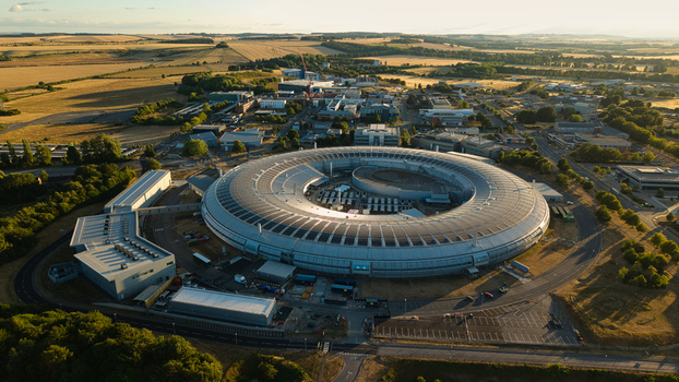 Aerial view of Diamond Light Source a circular synchrotron facility surrounded by greenery under golden hour light in Didcot United Kingdom.
