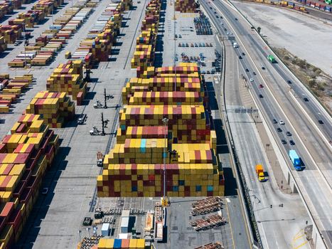 Aerial view of the Port of Long Beach with stacks of colorful shipping containers and a busy highway with vehicles Long Beach California United States. Aerial view of the Port of Long Beach with stacks of colorful shipping containers and a busy highway with vehicles Long Beach California United States.