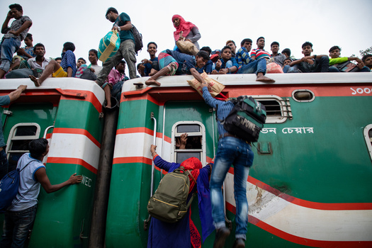 Dhaka Bangladesh 15 June 2018 View of crowds of people climbing and sitting on the roof of a train at Airport Railway Station during a busy travel period. Dhaka Bangladesh 15 June 2018 View of crowds of people climbing and sitting on the roof of a train at Airport Railway Station during a busy travel period.