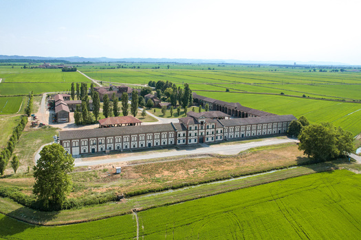 Aerial view of Tenuta Darola a historic agricultural estate with long symmetrical buildings and courtyards surrounded by expansive green rice fields in Trino Piemonte Italy. Aerial view of Tenuta Darola a historic agricultural estate with long symmetrical buildings and courtyards surrounded by expansive green rice fields in Trino Piemonte Italy.