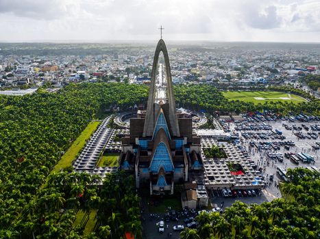 Aerial view of Basilica Nuestra Senora De La Altagracia surrounded by lush greenery and a large parking lot in Higuey La Altagracia Province Dominican Republic. Aerial view of Basilica Nuestra Senora De La Altagracia surrounded by lush greenery and a large parking lot in Higuey La Altagracia Province Dominican Republic.