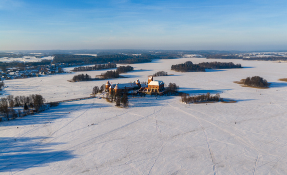 Aerial view of Trakai Island Castle surrounded by the frozen Lake Galve and a snow covered winter landscape under a clear blue sky in Trakai Vilniaus apskritis Lithuania.