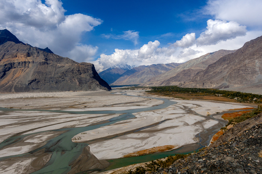 Aerial view of the Shigar Delta a braided river system with meandering channels and sandy banks set against dramatic mountains under a bright sky Shigar Gilgit Baltistan Pakistan. Aerial view of the Shigar Delta a braided river system with meandering channels and sandy banks set against dramatic mountains under a bright sky Shigar Gilgit Baltistan Pakistan.