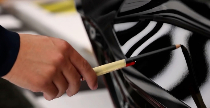 View of a technician marking a paint defect on the glossy black surface of a car body in Hiroshima Hiroshima Japan. View of a technician marking a paint defect on the glossy black surface of a car body in Hiroshima Hiroshima Japan.