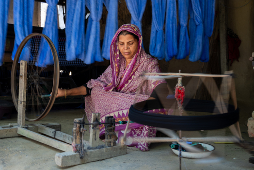 Joypurhat Rajshahi Division Bangladesh 22 September 2026 View of a woman operating a traditional spinning wheel in a workshop with blue yarn hanging in the background. Joypurhat Rajshahi Division Bangladesh 22 September 2026 View of a woman operating a traditional spinning wheel in a workshop with blue yarn hanging in the background.