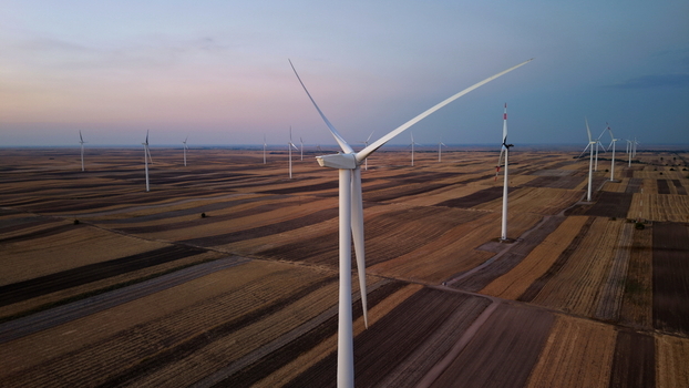 Aerial view of wind turbines standing in vast agricultural fields at dusk in Vladimirovac Vojvodina Serbia. Aerial view of wind turbines standing in vast agricultural fields at dusk in Vladimirovac Vojvodina Serbia.