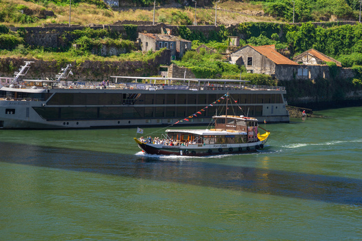 Aerial view of a traditional boat gliding on the Douro River juxtaposed against the backdrop of aged buildings Porto Porto District Portugal. Aerial view of a traditional boat gliding on the Douro River juxtaposed against the backdrop of aged buildings Porto Porto District Portugal.