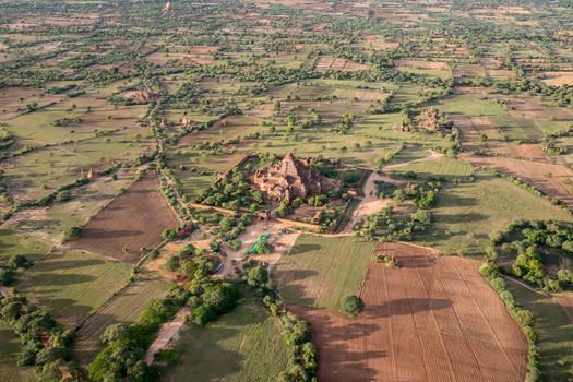 Aerial view of the massive Dhammayangyi Temple surrounded by ancient pagodas and lush green fields under warm sunlight in Old Bagan Mandalay Region Myanmar Burma. Aerial view of the massive Dhammayangyi Temple surrounded by ancient pagodas and lush green fields under warm sunlight in Old Bagan Mandalay Region Myanmar Burma.