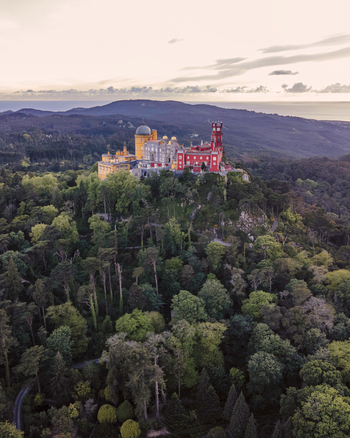 Aerial view of Pena Palace a colourful Romanticist castle building on hilltop during a beautiful sunset Sintra Lisbon Portugal.