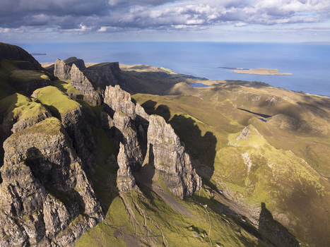 Aerial view of The Storr a dramatic rocky landscape on the Isle of Skye with jagged basalt pinnacles grassy slopes and the sea in the background in Scotland United Kingdom. Aerial view of The Storr a dramatic rocky landscape on the Isle of Skye with jagged basalt pinnacles grassy slopes and the sea in the background in Scotland United Kingdom.