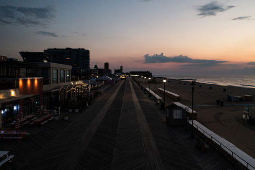 Aerial view of Asbury Park Beach and the historic boardwalk at sunset with warm glowing lights along the promenade and calm ocean waves in Asbury Park New Jersey United States. Aerial view of Asbury Park Beach and the historic boardwalk at sunset with warm glowing lights along the promenade and calm ocean waves in Asbury Park New Jersey United States.