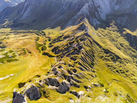 Aerial view of the rugged mountain ridge near Lunersee with green alpine meadows rocky slopes and dramatic shadows in the Vorarlberg Alps Vandans Vorarlberg Austria. Aerial view of the rugged mountain ridge near Lunersee with green alpine meadows rocky slopes and dramatic shadows in the Vorarlberg Alps Vandans Vorarlberg Austria.