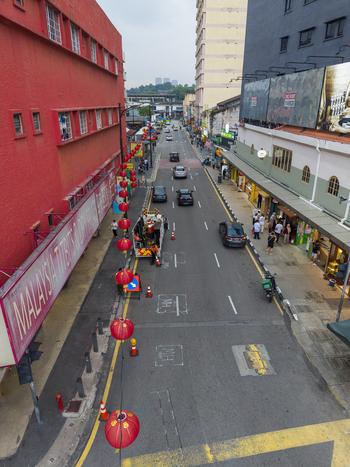 Kuala Lumpur Malaysia 09 March 2026 Aerial view of a busy street decorated with red lanterns featuring a vibrant red building and cars driving through the urban landscape.