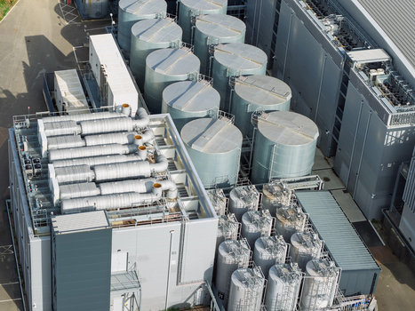 Aerial view of a modern data center facility featuring large industrial cooling tanks and extensive HVAC infrastructure in the United Kingdom. Aerial view of a modern data center facility featuring large industrial cooling tanks and extensive HVAC infrastructure in the United Kingdom.