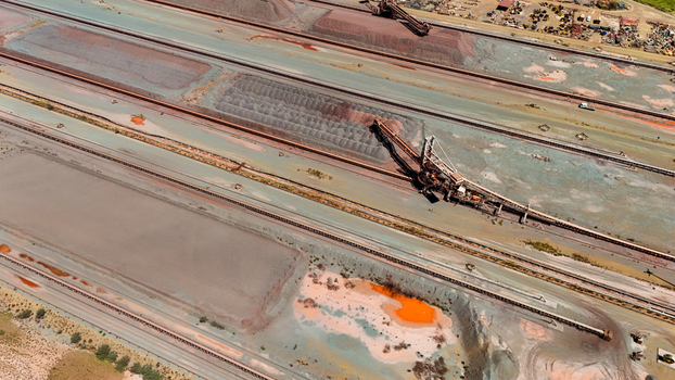 Aerial view of rust colored earth alongside the railway tracks where heavy machinery contrasts with the natural landscape South Africa. Aerial view of rust colored earth alongside the railway tracks where heavy machinery contrasts with the natural landscape South Africa.
