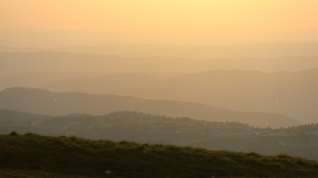 Aerial view of the rolling mountain ridges of Le Colomby de Gex during a hazy golden hour sunset in Echenevex Auvergne Rhone Alpes France. Aerial view of the rolling mountain ridges of Le Colomby de Gex during a hazy golden hour sunset in Echenevex Auvergne Rhone Alpes France.