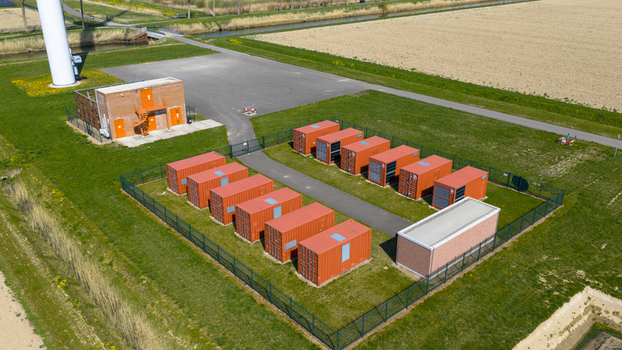 Aerial view of a battery energy storage system with orange containers and a wind turbine base in Middelharnis Zuid Holland Netherlands.