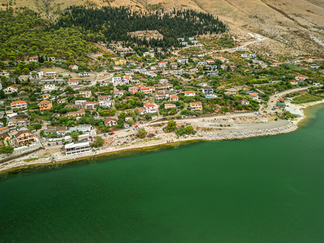 Aerial view of the village of Shiroka nestled on the shore of Lake Shkoder with lush green hills and mountains in the background in Shiroka Shkoder County Albania.