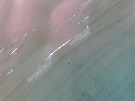 Aerial view of Gruinard Bay with pink sand and gentle turquoise waves washing over the shore Gruinard Scotland United Kingdom. Aerial view of Gruinard Bay with pink sand and gentle turquoise waves washing over the shore Gruinard Scotland United Kingdom.