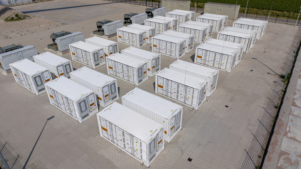 Aerial view of the Battery Energy Storage System at Wind Park featuring rows of white shipping containers used for energy storage on a paved site in Dronten Flevoland Netherlands. Aerial view of the Battery Energy Storage System at Wind Park featuring rows of white shipping containers used for energy storage on a paved site in Dronten Flevoland Netherlands.