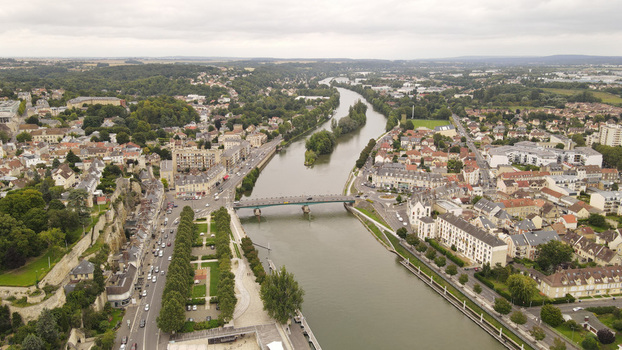 Aerial view of the Oise river flowing through the town of Pontoise with a bridge historic buildings and green spaces in Pontoise Ile de France France. Aerial view of the Oise river flowing through the town of Pontoise with a bridge historic buildings and green spaces in Pontoise Ile de France France.
