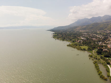 Aerial view of the town of Ajijic along the shoreline of Lake Chapala with lush greenery mountains and calm water in Ajijic Jalisco Mexico. Aerial view of the town of Ajijic along the shoreline of Lake Chapala with lush greenery mountains and calm water in Ajijic Jalisco Mexico.