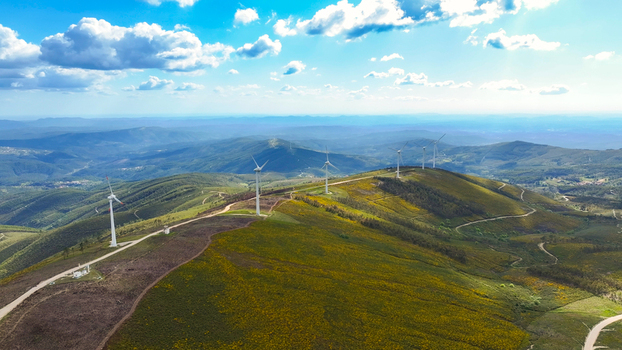Aerial view of wind turbines situated on rolling green hills with dirt access paths under a bright blue sky in Lisbon Lisbon Portugal. Aerial view of wind turbines situated on rolling green hills with dirt access paths under a bright blue sky in Lisbon Lisbon Portugal.