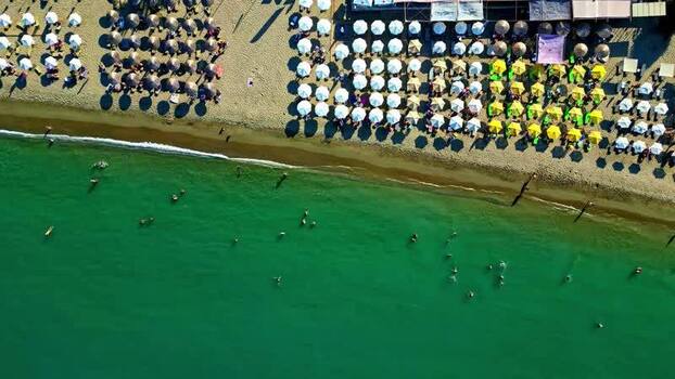 Aerial view of beach umbrellas and swimmers in Crete Greece.