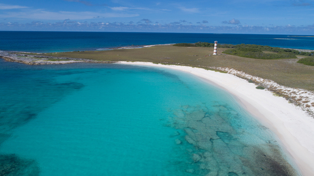 Aerial view of the Los Roques archipelago featuring a white sand beach turquoise Caribbean waters and a striped lighthouse on the coast of Los Roques Dependencias Federale Venezuela. Aerial view of the Los Roques archipelago featuring a white sand beach turquoise Caribbean waters and a striped lighthouse on the coast of Los Roques Dependencias Federale Venezuela.