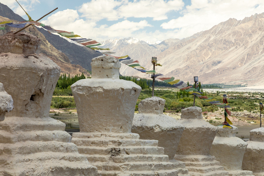 View of Charasa Gonpa with traditional white stupas and colorful prayer flags set against the dramatic mountain landscape of the Nubra Valley in Charasa Ladakh India.
