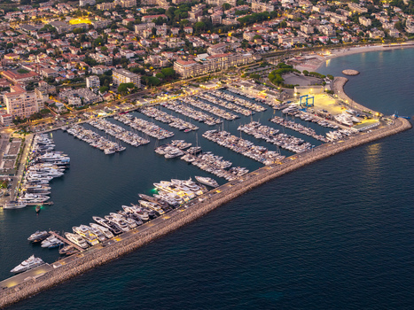 Aerial view of Port Vauban filled with luxury yachts and boats protected by a stone breakwater with the town of Antibes in the background. Antibes Provence Alpes Cote d Azur France. Aerial view of Port Vauban filled with luxury yachts and boats protected by a stone breakwater with the town of Antibes in the background. Antibes Provence Alpes Cote d Azur France.