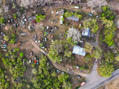 Aerial view of a sprawling junkyard with colorful car bodies scattered amidst trees and buildings creating a vibrant yet chaotic landscape Palisade Colorado USA. Aerial view of a sprawling junkyard with colorful car bodies scattered amidst trees and buildings creating a vibrant yet chaotic landscape Palisade Colorado USA.