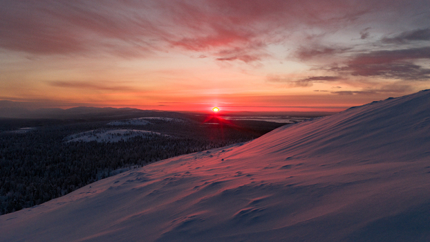 Aerial view of the snow covered slopes of Luosto fell during a vibrant sunset over the vast arctic forests in Sodankyla Lapland Finland. Aerial view of the snow covered slopes of Luosto fell during a vibrant sunset over the vast arctic forests in Sodankyla Lapland Finland.