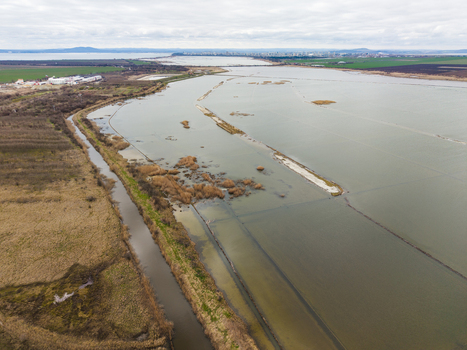 Aerial view of Lake Atanasovsko showing the salt pans and wetlands with the city skyline in the distance under an overcast sky in Burgas Burgas Bulgaria. Aerial view of Lake Atanasovsko showing the salt pans and wetlands with the city skyline in the distance under an overcast sky in Burgas Burgas Bulgaria.