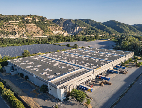 Le Pouzin France 04 July 2026 Aerial view of the SKIPPER Logistique warehouse and distribution center with loading docks trucks and adjacent solar panel fields near rolling hills. Le Pouzin France 04 July 2026 Aerial view of the SKIPPER Logistique warehouse and distribution center with loading docks trucks and adjacent solar panel fields near rolling hills.