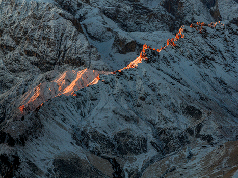 Aerial view of jagged peaks dusted with fresh snow kissed by the warm glow of the setting sun creating a stark contrast of light and shadow Seiser Alm South Tyrol Italy.