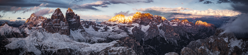Aerial view of Tre Cime di Lavaredo and Croda dei Torni crowned with snow at sunset contrasting with the dark shadows below Dolomites Italy. Aerial view of Tre Cime di Lavaredo and Croda dei Torni crowned with snow at sunset contrasting with the dark shadows below Dolomites Italy.