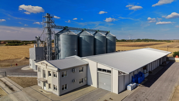 Aerial view of the grain storage silo facility featuring large metal silos a modern warehouse and an office building set amidst agricultural fields in Bavaniste Vojvodina Serbia.