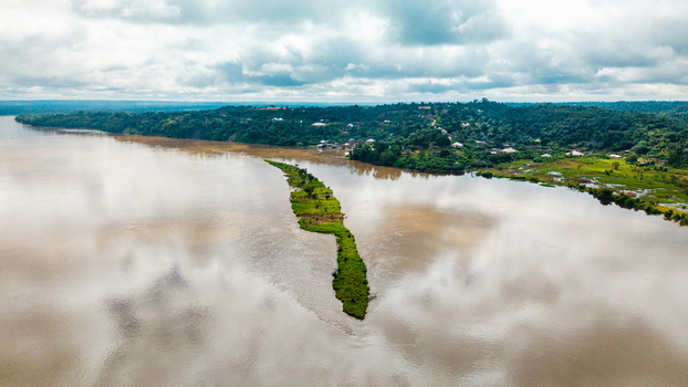 Aerial view of the Cross River with a long green island lush vegetation along the banks and a cloudy sky in Itu Akwa Ibom Nigeria. Aerial view of the Cross River with a long green island lush vegetation along the banks and a cloudy sky in Itu Akwa Ibom Nigeria.