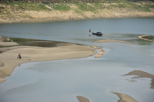 Kushtia District Khulna Division Bangladesh 10 March 2020 View of a river with sandbanks a small wooden boat and a person walking along the shore. Kushtia District Khulna Division Bangladesh 10 March 2020 View of a river with sandbanks a small wooden boat and a person walking along the shore.